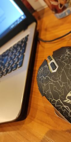 a computer mouse sitting on top of a wooden desk next to an open laptop computer