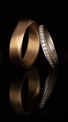 two gold wedding rings with diamonds on black background