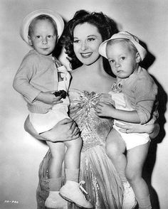 an old black and white photo of a woman holding two children