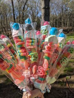 a person holding up a bunch of candy covered lollipops in plastic wrappers