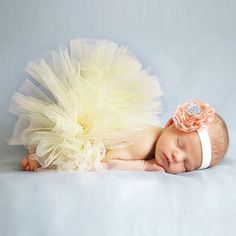 a newborn baby girl wearing a tutu and headband