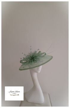 Grace and glamour hatinator in Pistachio green sinamay.  A crisp gentle curved brim is complemented with a low crown, which has been embellished with green pearls.  A sinamay bow plays host to a green starburst feather flower, whilst a pair of ostrich quills add a little drama.  Sits on a headband.  This item has sold, however, similar pieces can be made in a variety of colours.  Please ask for details.  As every piece is handmade, some differences can occur from the photos listed on this site. Elegant Green Fascinator For Church, Elegant Green Headpiece For Church, Elegant Green Church Fascinator, Green Evening Fascinator Hat, Green Fitted Fascinator For Evening, Spring Fascinator With Sinamay And Curved Brim, Sinamay Fascinator Hat For Spring, Spring Church Fascinator In Sinamay, Spring Sinamay Fascinator Hat