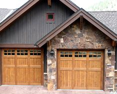 two brown garage doors in front of a stone and wood house with mountains in the background