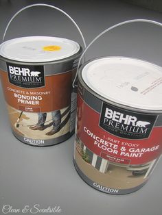 two buckets of paint sitting next to each other on top of a gray surface