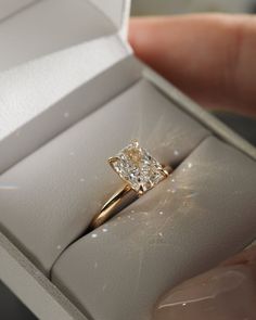 a diamond ring is being held in a white box with the light shining on it