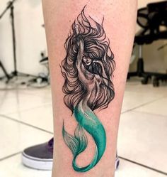 a woman's leg with a green mermaid tattoo on the side of her leg