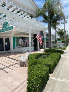 a white building with an american flag on the front and green trimming around it