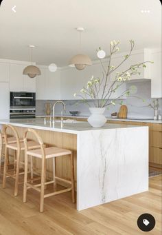 a large kitchen island with stools next to it and a vase filled with flowers