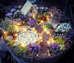 a small garden with flowers and lights in the center is displayed on top of a barrel