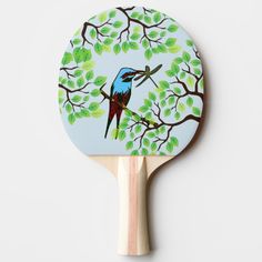 a ping pong paddle with a painting of a bird perched on a tree branch