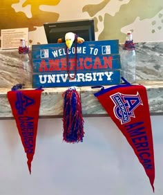 two red and blue pennants are hanging from a wall with an american university sign on it