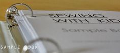 a pair of glasses sitting on top of a binder next to a paper with the words sewing with kids written on it