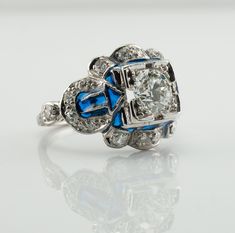 This vintage ring is crafted in solid 14K White Gold (carefully tested and guaranteed). The center Old European cut diamond is .75 carat of VS1 clarity and G color! It is accented with 18 mine cut diamonds of SI1-I1 clarity and H color totaling .38 carat. The blue enamel is in mint condition. The top of the ring measures 13mm top to bottom. The setting elevates 6mm high above finger. Size 4.5 (sizable). The ring weighs 4.2 grams. Great vintage condition. T5183455 Antique Blue Diamond Ring For Formal Occasions, Blue Diamond Enamel Ring Fine Jewelry, Blue Diamond Enamel Ring For Formal Occasions, Blue Enamel Diamond Ring Fine Jewelry, Formal Blue Enamel Diamond Ring, Antique Blue Diamond Ring For Anniversary, Antique Blue Diamond Rings, Luxury Diamond Enamel Ring For Wedding, Luxury Diamond Enamel Wedding Ring