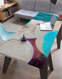 a living room with a couch, table and laptop on the floor in front of it