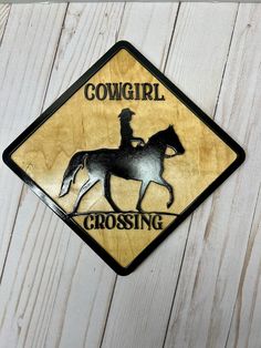 a cowgirl crossing sign mounted to the side of a wooden wall