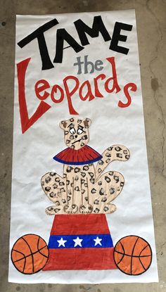 a sign that says tame the leopards with a teddy bear on top of a basketball