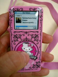 a person holding a pink hello kitty mp3 player with a ribbon around it's neck