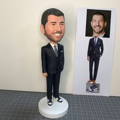 a personalized bobble head next to a photo of a man in a suit