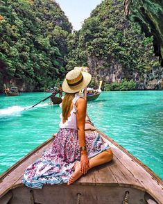 a woman in a straw hat is sitting on a boat looking out at the water