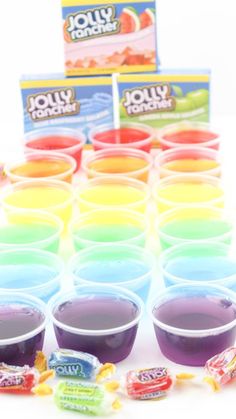 jelly shots are lined up on a table with candy bars in front of them,