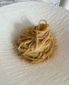 a white plate topped with pasta covered in powdered sugar on top of a table