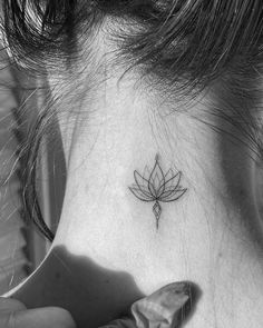 a woman's neck with a small lotus tattoo on it