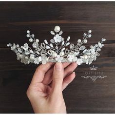 a hand holding a tiara on top of a wooden table