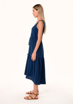 A classic navy blue bohemian midi dress made with soft cotton gauze and featuring contrast thread details. Cotton gauze Relaxed fit Sleeveless Mid-length Tiered skirt Scoop neckline with contrast thread Tassel tie drawstring waist Side pockets Bohemian summer dress Crafted from soft cotton gauze, this sleeveless mid-length dress is designed to keep you cool and comfortable all season long. The contrast thread detail adds a touch of unique charm, while the scooped neckline flatters your décolleta Blue Beach Dress With Tie Fastening, Bohemian Sleeveless Maxi Dress With Drawstring, Summer Midi Dress With Tie Fastening, Summer Linen Dress With Drawstring, Casual Blue Dresses With Tie Fastening, Casual Blue Dress With Tie Fastening, Summer Midi-length Dress With Drawstring, Summer Midi Length Dress With Drawstring, Navy Casual Beach Dress