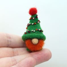 a hand holding a tiny christmas tree ornament