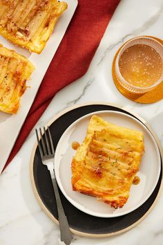 some food is sitting on a plate with a fork and knife next to it, along with other foods