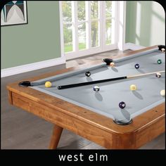 a pool table with several billiards on it and the words west elm above it