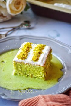 a piece of cake sitting on top of a plate covered in green liquid and sprinkled with white frosting