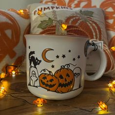 a white coffee cup decorated with pumpkins and jack - o'- lantern lights