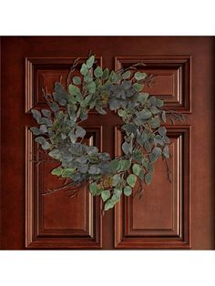 a wooden door with a wreath hanging on it's side and leaves in the middle