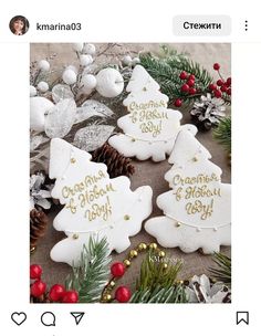 christmas cookies decorated with gold lettering and pine cones are on the table next to other decorations