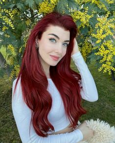 a woman with long red hair sitting in the grass