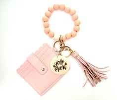 a pink purse charm with a tassel hanging from it's front and side