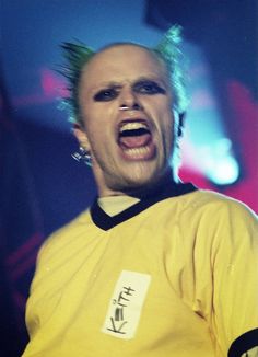 a man with his mouth open wearing a yellow shirt and piercings on it's head