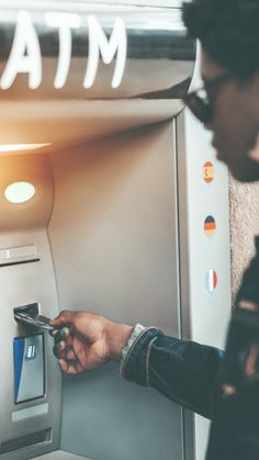 a man is using an atm machine to pay for his cell phone or credit card