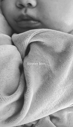 a black and white photo of a baby wrapped in a blanket with the words forever love written on it