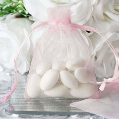 a bag filled with white balls sitting on top of a table next to some flowers