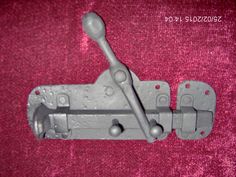 a pair of metal latches on a pink cloth with holes in the middle and two screws at the end