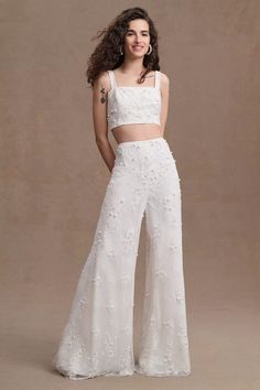 a woman in a white crop top and wide legged pants