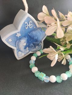 a blue and white beaded bracelet with an elephant on it next to some flowers