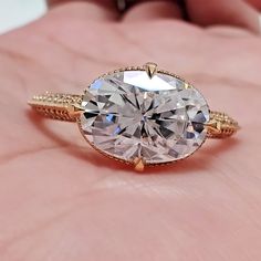 a close up of a person's hand holding a ring with a large diamond