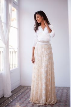 a woman in a long dress standing by a window