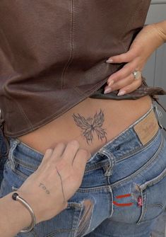 a woman with a butterfly tattoo on her stomach is looking down at the bottom of her jeans