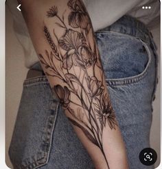 a woman's arm with flowers and leaves tattooed on the side of her arm