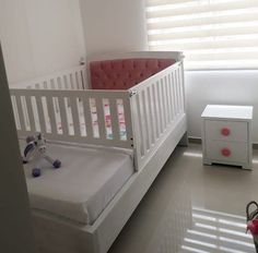 a baby's room with a white crib and pink furniture