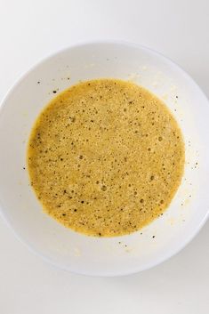 a white bowl filled with yellow liquid on top of a table